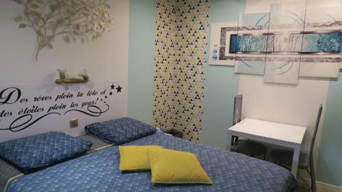 a bedroom with two beds and a table and a writing on the wall at Les Victoriennes in Verdun-sur-Meuse