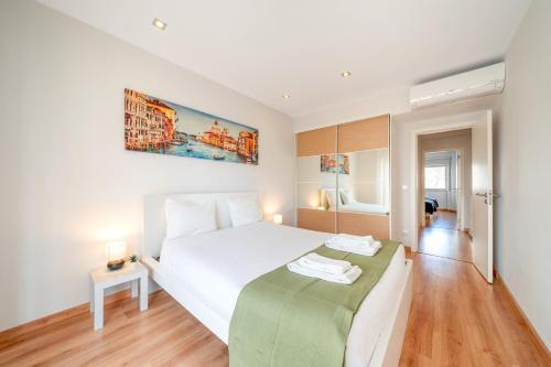 a bedroom with a white bed with a green blanket at GuestReady - Retreat in Almada in Almada