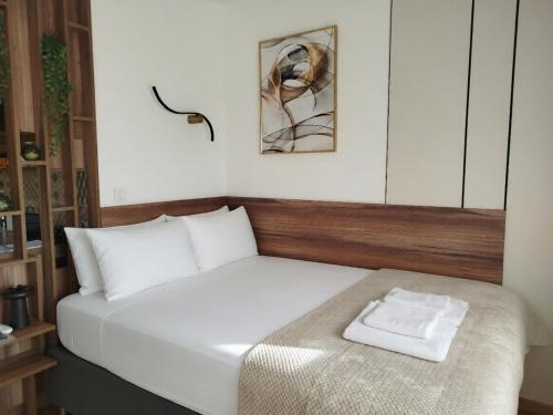 a bedroom with a white bed with a wooden headboard at City Studio in Smederevo