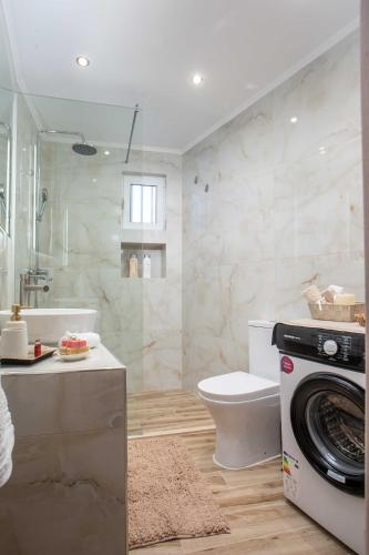 a bathroom with a toilet and a washer and dryer at Hara's Cozy Apartment with Private Parking in Rhodes Town