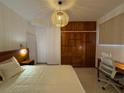 a bedroom with a bed and a chair and a chandelier at BoHo Galapagos in Puerto Ayora