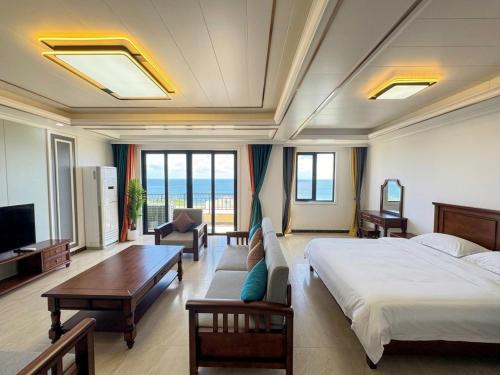 a bedroom with a bed and a couch and a tv at Seaview Garden Hotel & Residences in Trinity