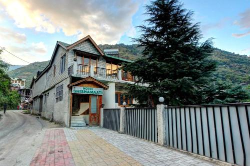 an old house with a fence and a tree at Hotel O Shishamaati in Kulu