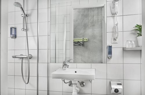 a white bathroom with a sink and a shower at Smarthotel Tromsø in Tromsø
