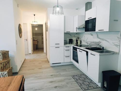 a kitchen with white cabinets and a wooden floor at Casa ELYVMY in Zonza