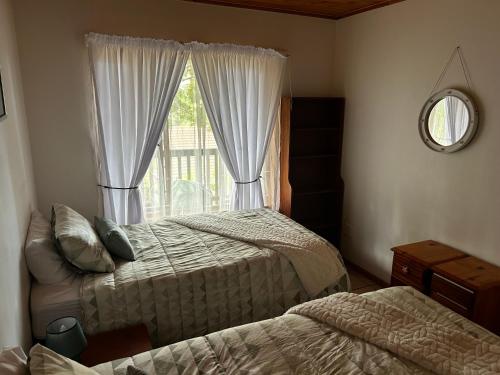 a bedroom with two beds and a window at Die Anker Kothuis in Southbroom