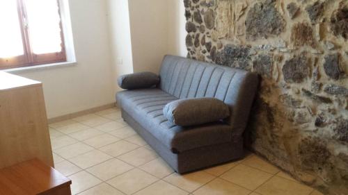 a blue couch sitting next to a stone wall at Casa Michele in Pau