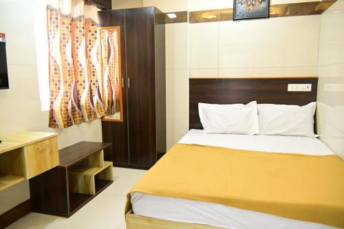a small bedroom with a bed and a desk at VRJInn in Vellore
