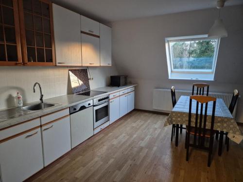 a kitchen with white cabinets and a table with chairs at Zimmervermietung Lena in Lengerich