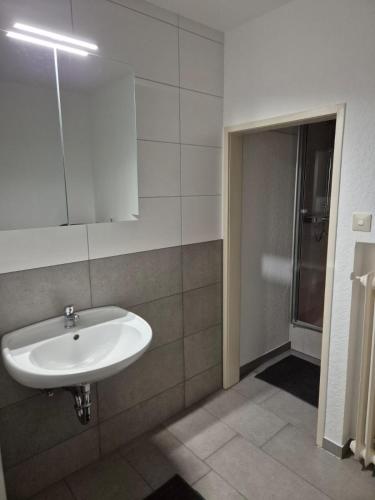 a bathroom with a sink and a mirror and a shower at Zimmervermietung Lena in Lengerich