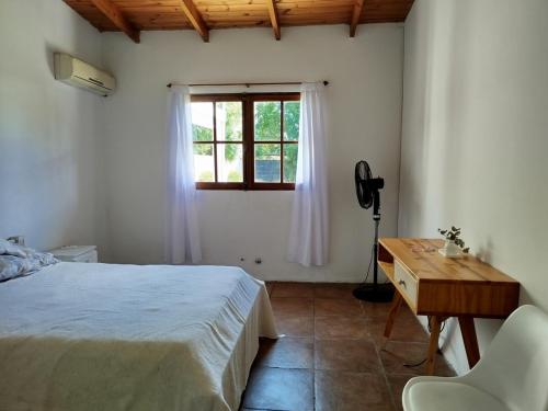 a bedroom with a bed and a desk and a window at Casa Quinta Malu in Gualeguaychú