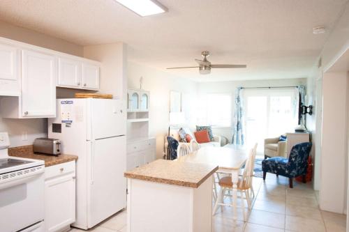 a kitchen with a white refrigerator and a table at Salty Dune 2BR Beach Condo w Pools in Gulf Shores