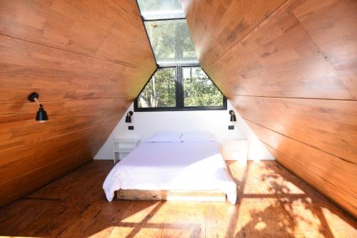 a bed in a room with wooden walls and a window at Cabaña Gokotta, Punta del Bosque in Huasca de Ocampo