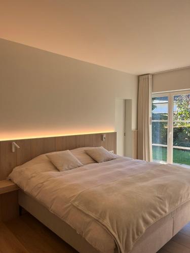 a bedroom with a large bed and a window at Villa Kokeliko in Kuurne
