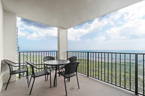 a balcony with a table and chairs and the ocean at Barefoot Getaway in Orange Beach