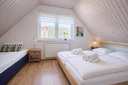 two beds in a attic bedroom with a window at Ferienhaus Klüver in Kühlungsborn