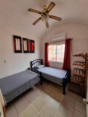 a bedroom with two beds and a ceiling fan at Casa de playa El Artesano in Ixtapa
