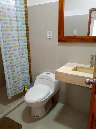 a bathroom with a white toilet and a sink at Fifi Shouse Ayangue in Santa Elena