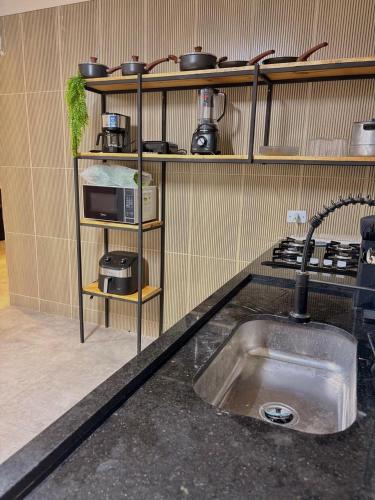 a kitchen with a sink and a shelf with pots and pans at Rancho de férias in Japaratinga