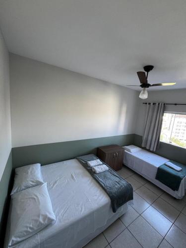 a bedroom with two beds and a ceiling fan at Apartamento com varanda in Lavras