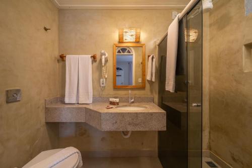 a bathroom with a sink and a shower and a toilet at Pousada Jangadeiro in Porto Seguro