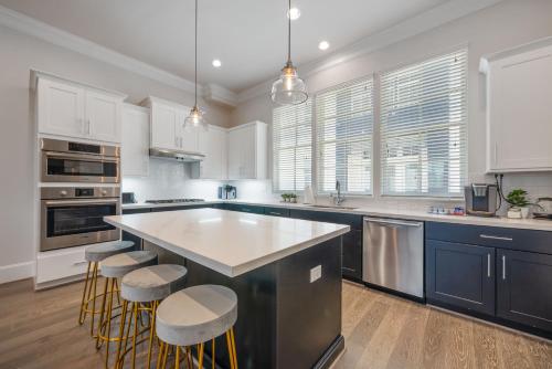 a kitchen with white cabinets and a large island with bar stools at Luxury DT Condo, Game Room! in Houston