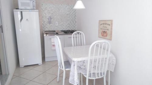 eine Küche mit einem Tisch und Stühlen sowie einem Kühlschrank in der Unterkunft Cabo Frio Flats in Cabo Frio