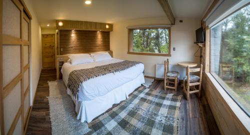 a bedroom with a bed and a table and a window at Casa Bosque Chiloé in Dalcahue