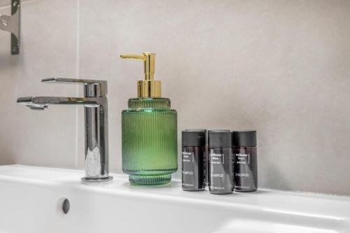 a green soap dispenser sitting on top of a sink at XTN Chill House Aeroport with parking in Cluj-Napoca