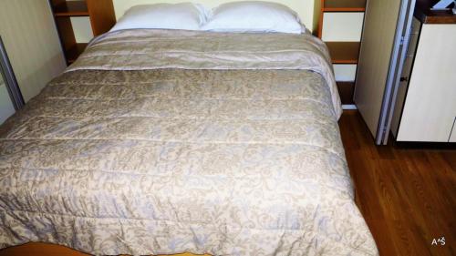 a bed in a small room with a bedspread at Nidos Poilsine Studio in Nida