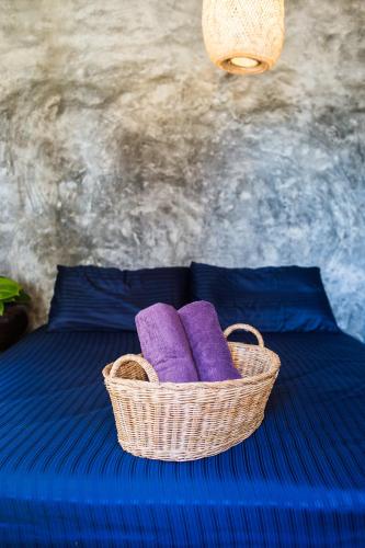 a basket sitting on top of a bed with purple pillows at Sweet Life Guesthouse in Ko Lanta