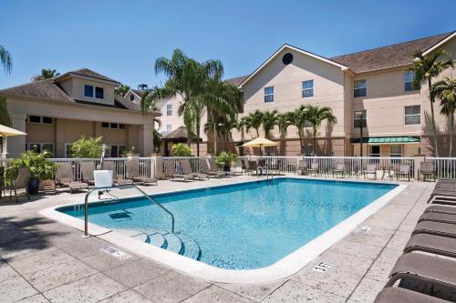 a swimming pool with chairs and a building at Homewood Suites by Hilton Fort Myers in Fort Myers