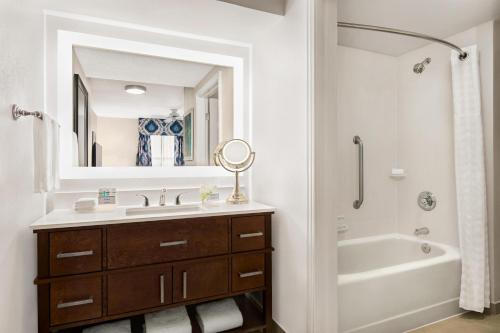 a bathroom with a sink and a tub and a mirror at Homewood Suites by Hilton Fort Myers in Fort Myers