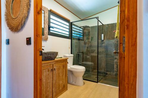 a bathroom with a toilet and a glass shower at Revatua Lodge Puuru - Piscine privée et Petit-déjeuner inclus in Niumaa
