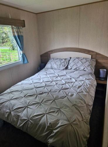 a large bed in a bedroom with a window at haggerston castle lakeside east 27 in Goswick Station