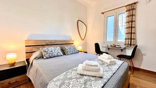a bedroom with a bed with two chairs and a window at Elina's Rooms in Poros
