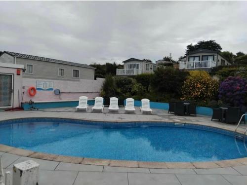 a swimming pool with chairs and a house in the background at 2 Vale Park in Fishguard