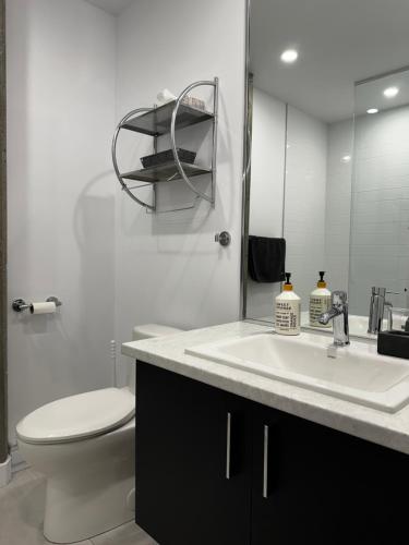 a bathroom with a sink and a toilet and a mirror at Condo "Imagine" - stationnement privé inclus in Quebec City