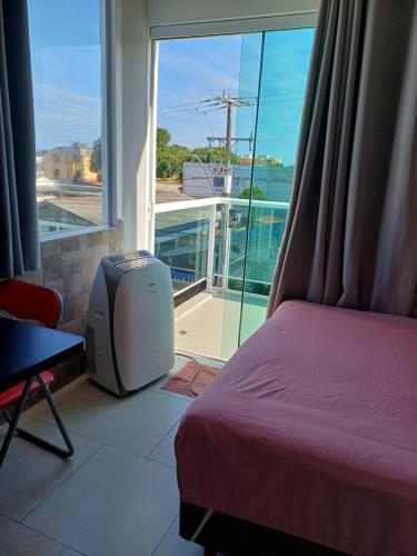a bedroom with a bed and a tv and a balcony at Suíte praia de leste in Pontal do Paraná