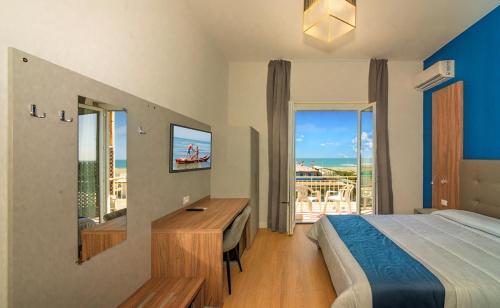 a bedroom with a bed and a desk and a balcony at Hotel Rialto Suisse in Lido di Camaiore