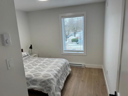 a white bedroom with a bed and a window at Modern Townhouse Room in Fredericton