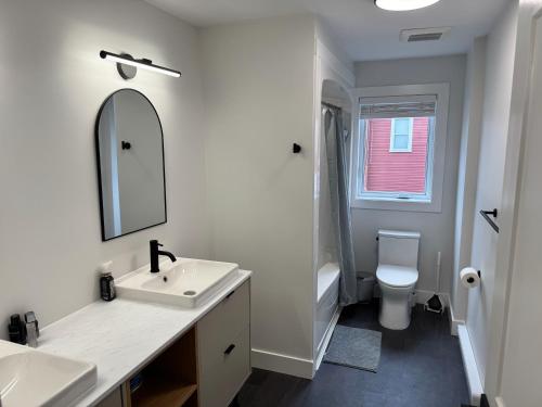 a white bathroom with a sink and a toilet at Modern Townhouse Room in Fredericton