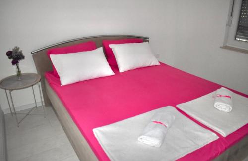 a bed with pink and white sheets and a table at Suncrest in Mostar