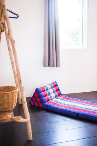 a red white and blue pillow on the floor next to a window at Sweet Life Guesthouse in Ko Lanta