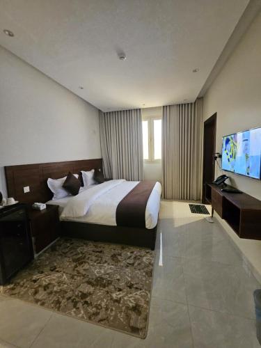 a hotel room with a bed and a flat screen tv at أجنحة توليب للشقق المخدومة in Hafr Al-Batin