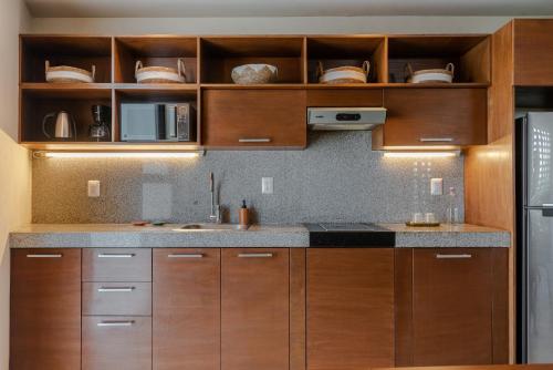 a kitchen with wooden cabinets and a sink and a refrigerator at Hola Donceles Suites in Cancún