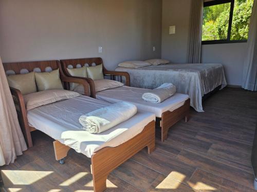 a room with three beds and a window at Riviera Barão de Antonina - Chalés na Represa - Piscina vista incrível in Barão de Antonina