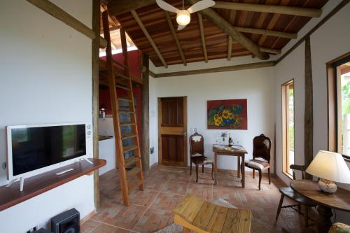 a living room with a television and a table and chairs at Villa Girassol in Ilhabela