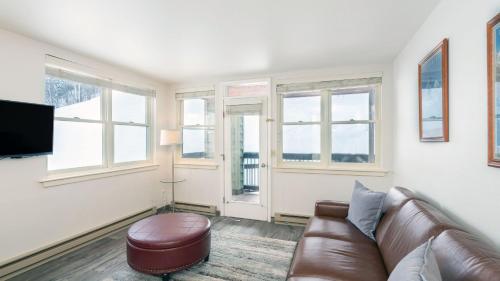 a living room with a leather couch and windows at Etta Place 1 by AvantStay Ski In Ski Out Unit w Views of the Slopes in Telluride