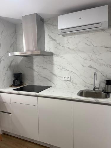 a white kitchen with a sink and a counter top at Casa da Fonte in Rianjo